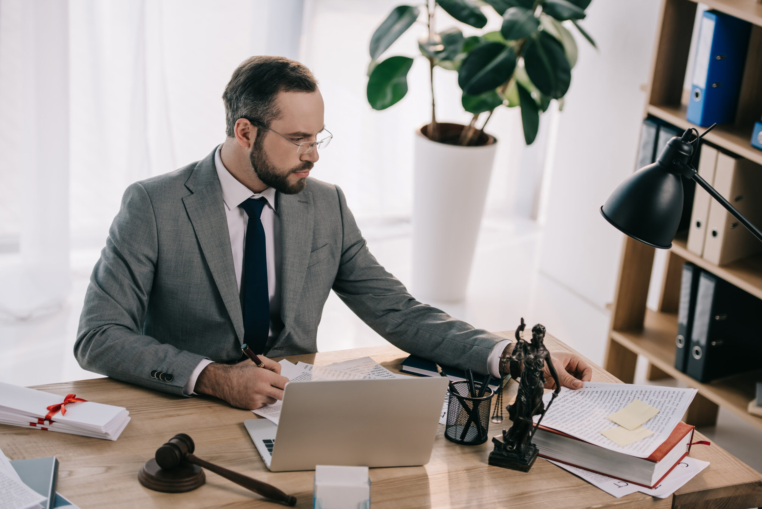 portrait of lawyer in suit working at workplace with laptop in office